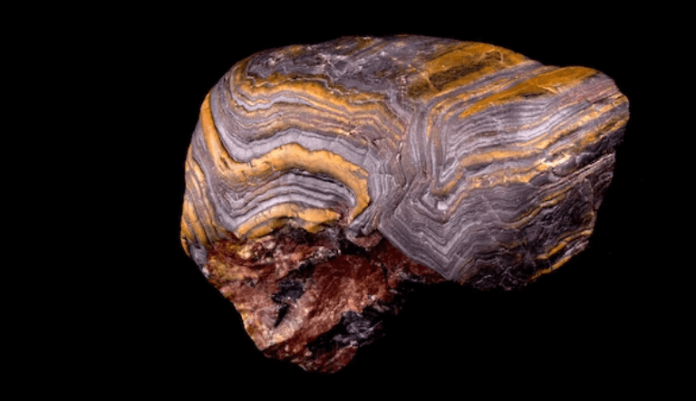 Iron-rich rock showing reddish-brown rust color due to oxidation chemical weathering with visible cracks and soil formation.